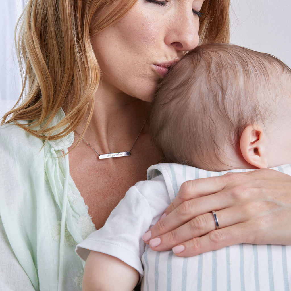 woman wearing skinny bar necklace hugging baby