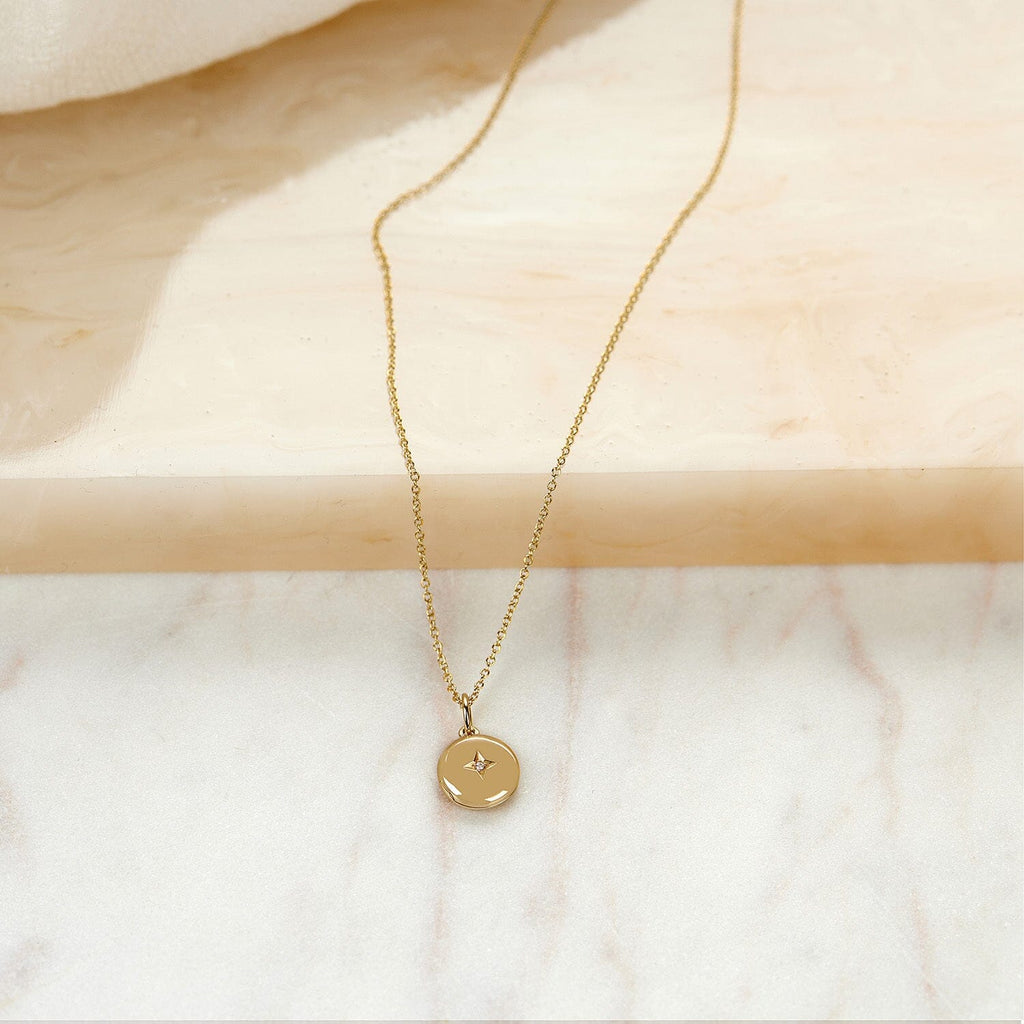 round gold mini locket necklace on marble background