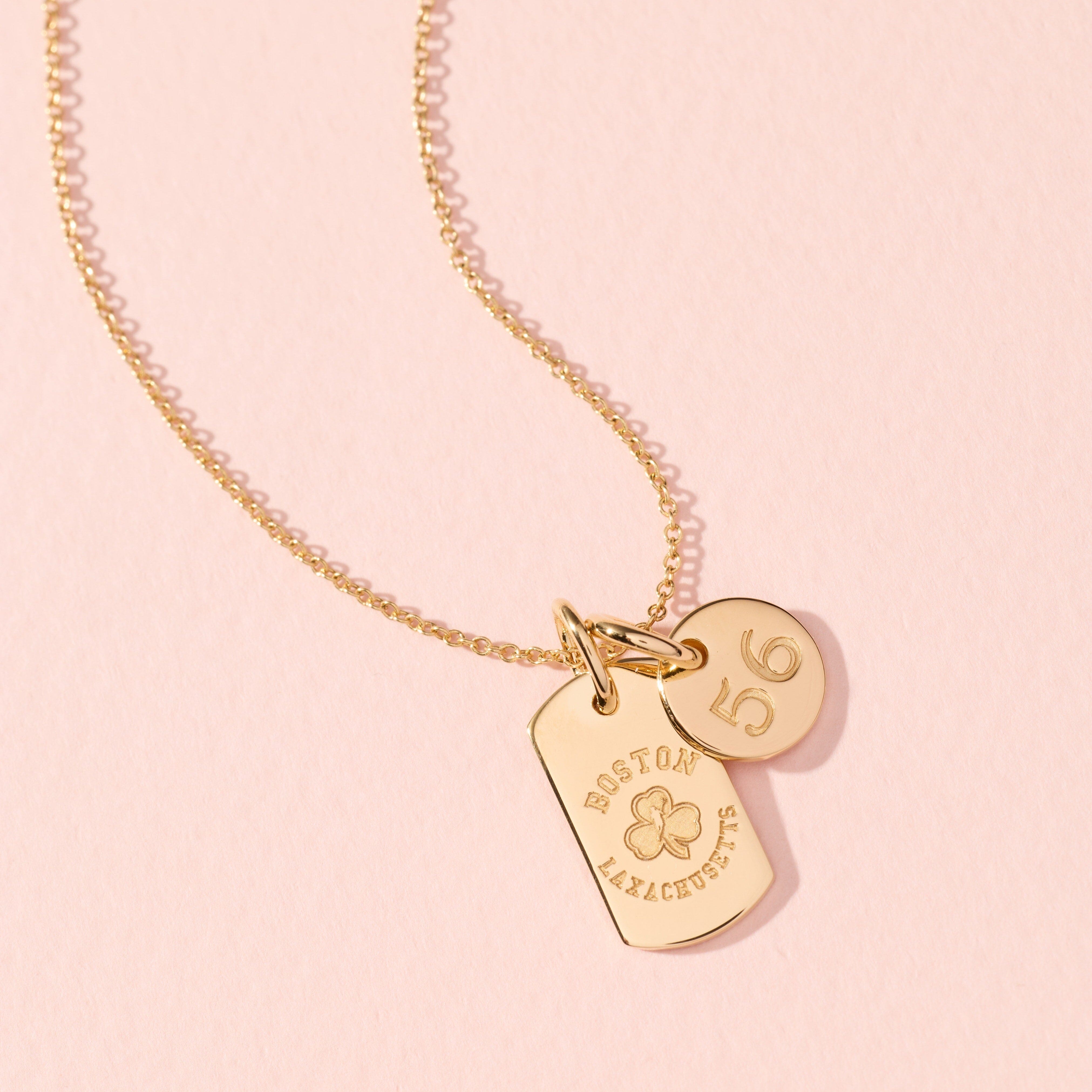 Gold necklace with heart-shaped tags on a pink background
