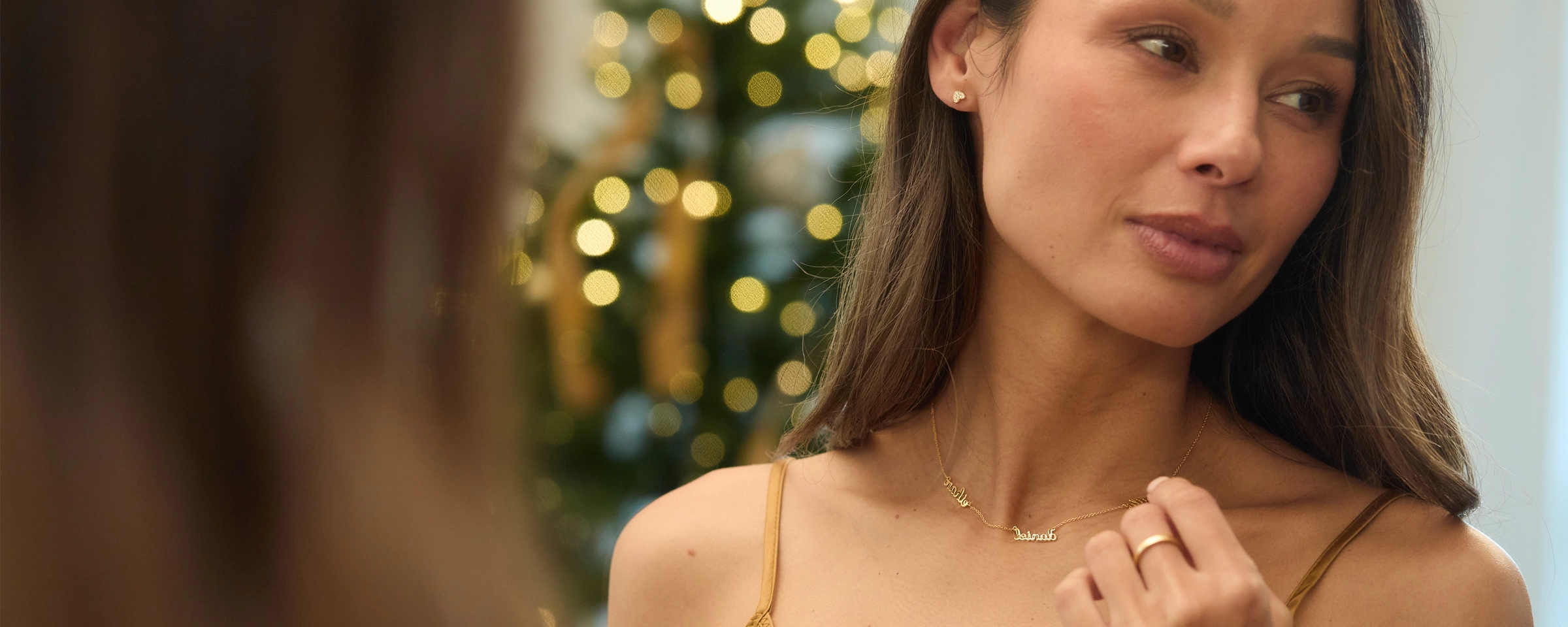 woman wearing tiny tags jewelry looking in mirror