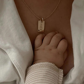 Woman holding a baby wearing a Tiny Tags necklace
