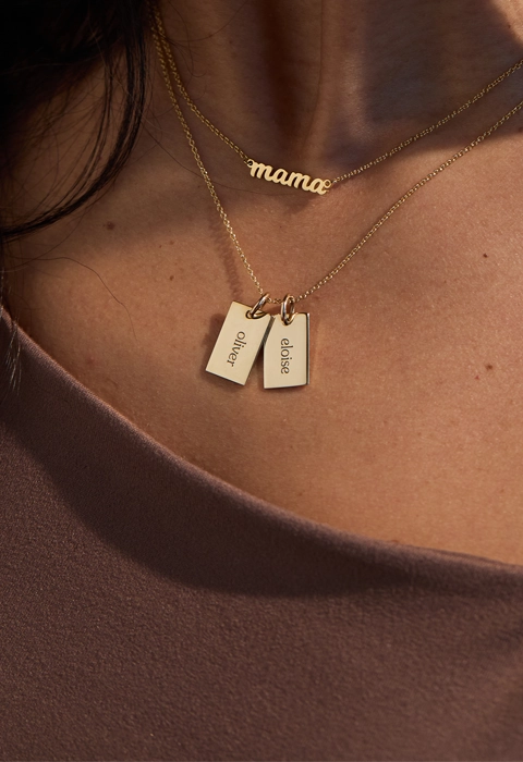 woman wearing a brown shirt with gold mama nameplate with two gold mini dog tags