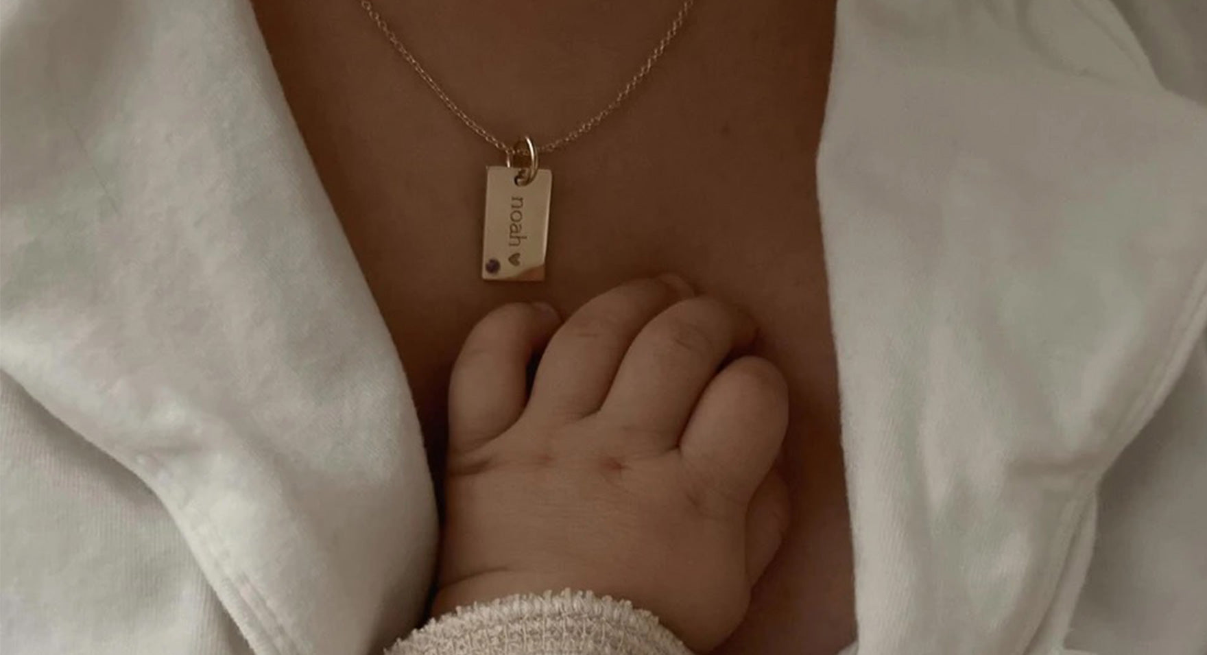 baby hand reaching for mini dog tag necklace
