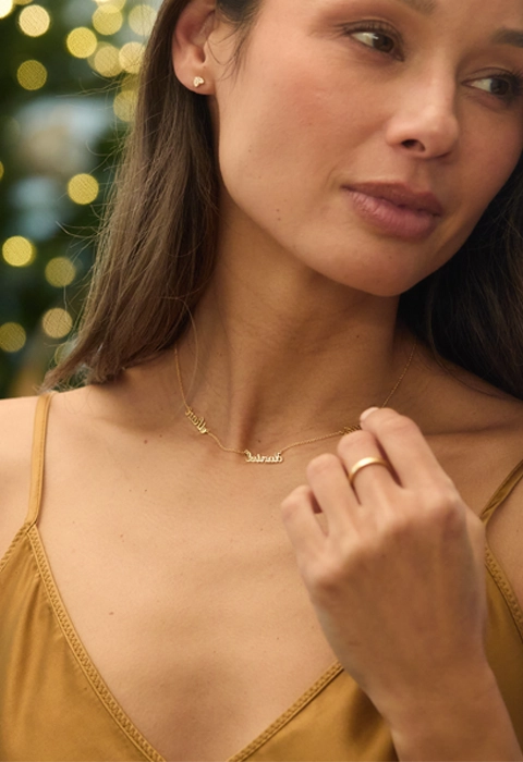 woman wearing tiny tags jewelry looking in mirror