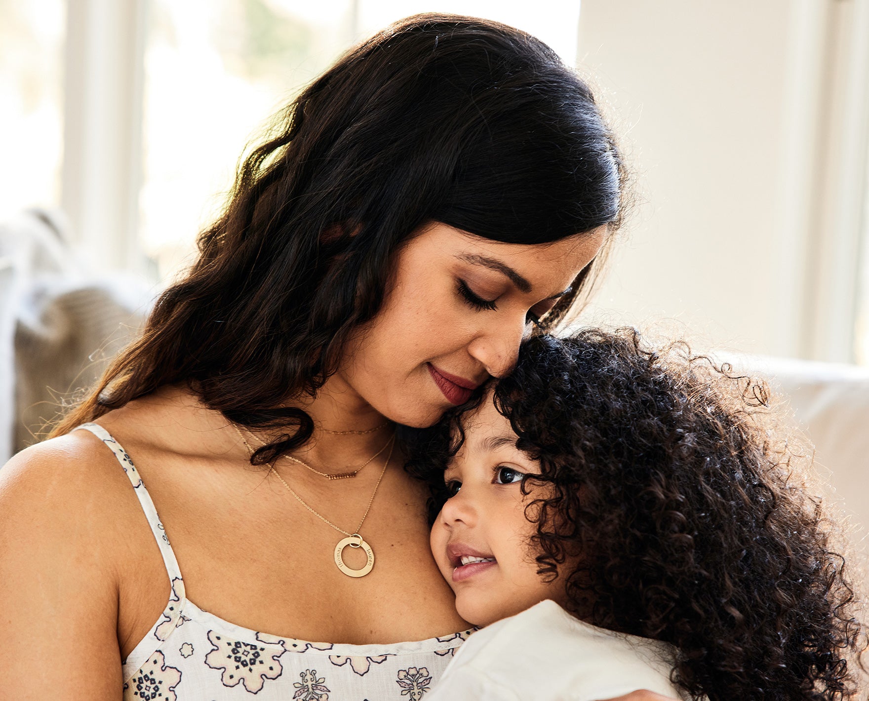 woman hugging daughter wearing a circle pendant necklace